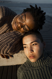 Smiling woman leaning on friend head while lying on bench