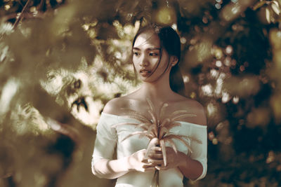 Thoughtful young woman holding plant