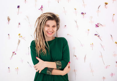 Portrait of smiling young woman standing against wall