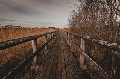 Footbridge over footpath amidst field against sky