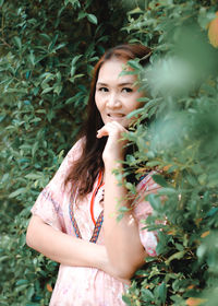 Portrait of smiling woman standing against plants