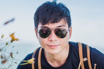 Portrait of young man wearing sunglasses against sky