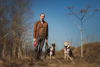 Man with dog standing on field against sky