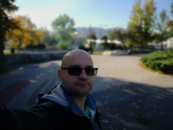 Portrait of mid adult man wearing sunglasses standing on footpath against sky