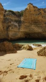 Towel on sand against cliff at beach