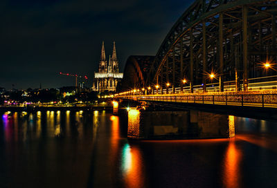 Illuminated bridge over river at night