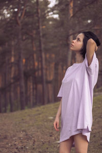 Full length of woman standing on field in forest