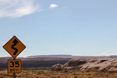 Road sign on cliff against blue sky