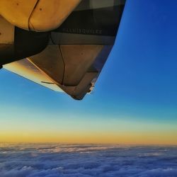 Airplane wing against sky during sunset