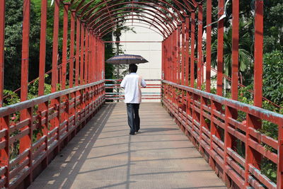 Rear view of man walking on footbridge