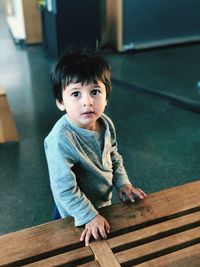 Portrait of cute boy by table at home