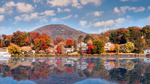 Trees by lake against sky during autumn