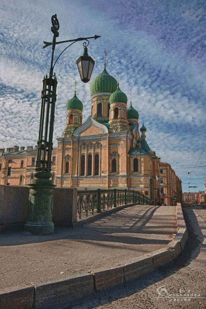 architecture, building exterior, built structure, sky, street light, transportation, cloud - sky, street, railing, water, incidental people, day, outdoors, city, mode of transport, cobblestone, lighting equipment, sidewalk, cloud, sunlight