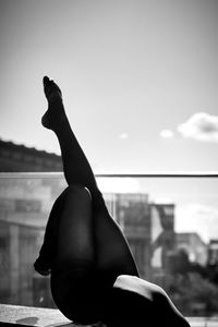 Low section of seductive woman dancing on building terrace against sky