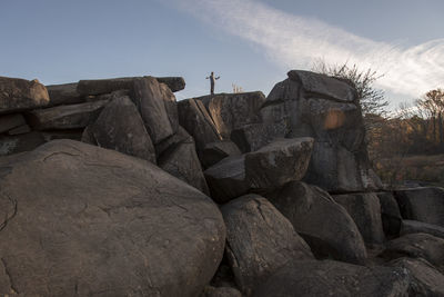 Distant view of man standing on rocks against sky