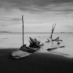 Abandoned boat on beach against sky