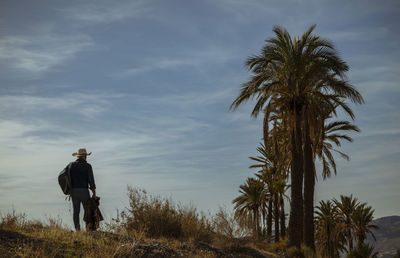 Rear view of adult man in cowboy hat walking on dirt road in desert. almeria, spain