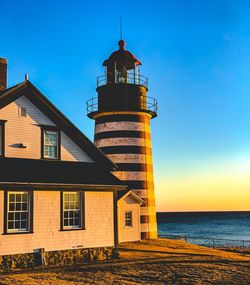 Lighthouse amidst sea and buildings against sky