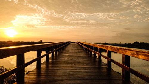 Bridge over sea against sky during sunset