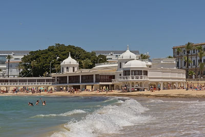 Group of people on building by sea against clear sky