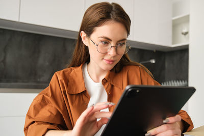 Young woman using digital tablet while sitting at home