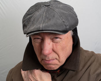 Close-up portrait of man wearing hat against wall
