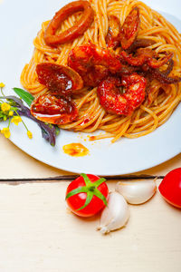 Italian seafood spaghetti pasta on red tomato sauce over white rustic wood table