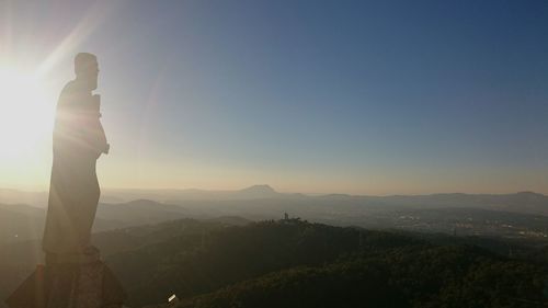 Silhouette woman standing on mountain against sky during sunset