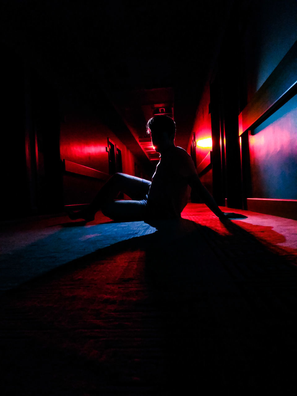 FULL LENGTH OF YOUNG MAN SITTING IN ILLUMINATED UNDERGROUND