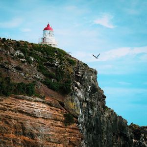 Low angle view of lighthouse on cliff against sky