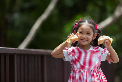 Portrait of smiling girl holding bread outdoors