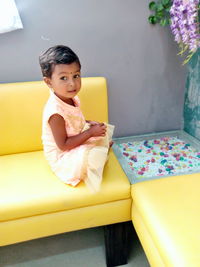 Portrait of boy sitting on sofa at home