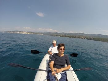 People kayaking in sea against sky