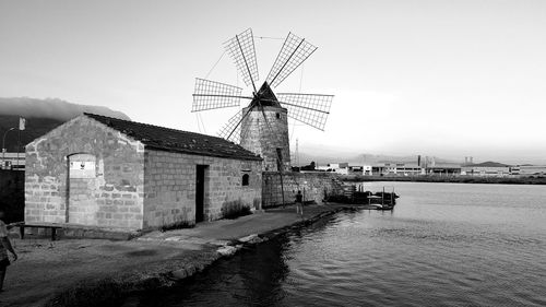Traditional windmill by canal against sky