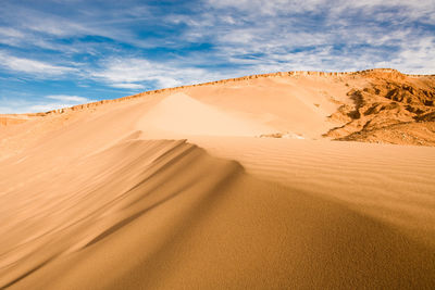 Sand dunes in desert against sky