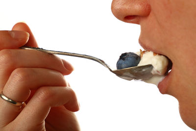 Close-up of person eating ice cream over white background