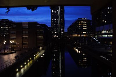 Illuminated bridge over river amidst buildings in city at night