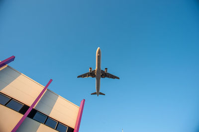 Low angle view of airplane flying against clear blue sky