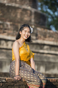 Full length of a smiling young woman sitting at temple