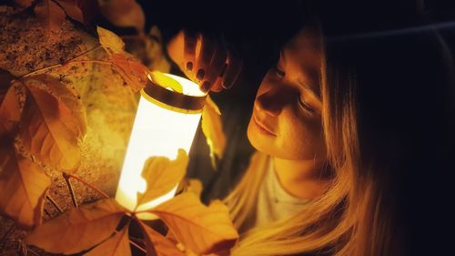 Close-up portrait of young woman holding lamp