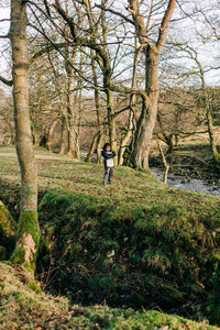 Woman standing by tree in forest