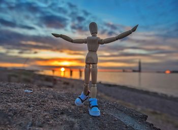 Toy on shore at beach against sky during sunset