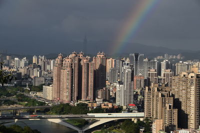 Aerial view of rainbow over buildings in city against sky