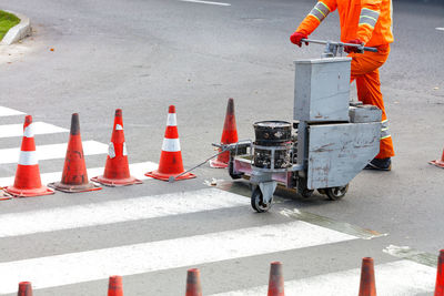 A road worker uses a power trolley to renew the markings of a pedestrian crossing.