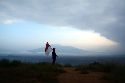 Woman standing on mountain against sky