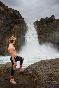 Full length of shirtless man standing on rock