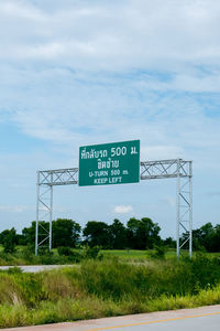 Information sign by road on field against sky