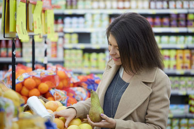 Smiling woman buying fruits at supermarket