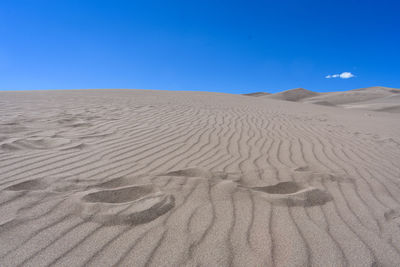 Sand dunes in desert against clear blue sky