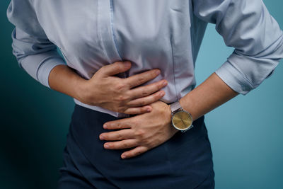 Midsection of couple holding hands against blue background